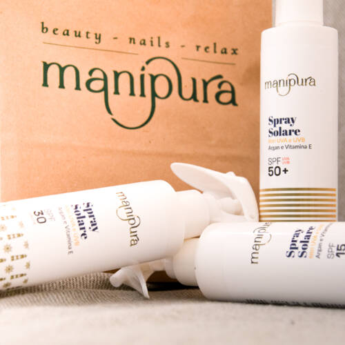 Spray solari Manipura con SPF 15, 30 e 50+ disposti davanti a una shopper del centro estetico.
