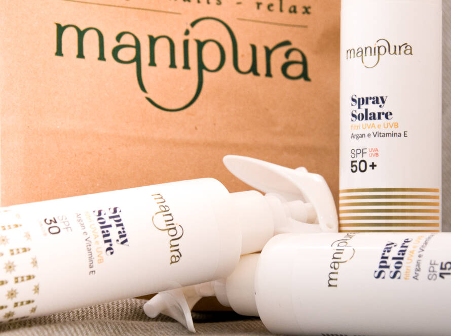 Spray solari Manipura con SPF 15, 30 e 50+ disposti davanti a una shopper del centro estetico.