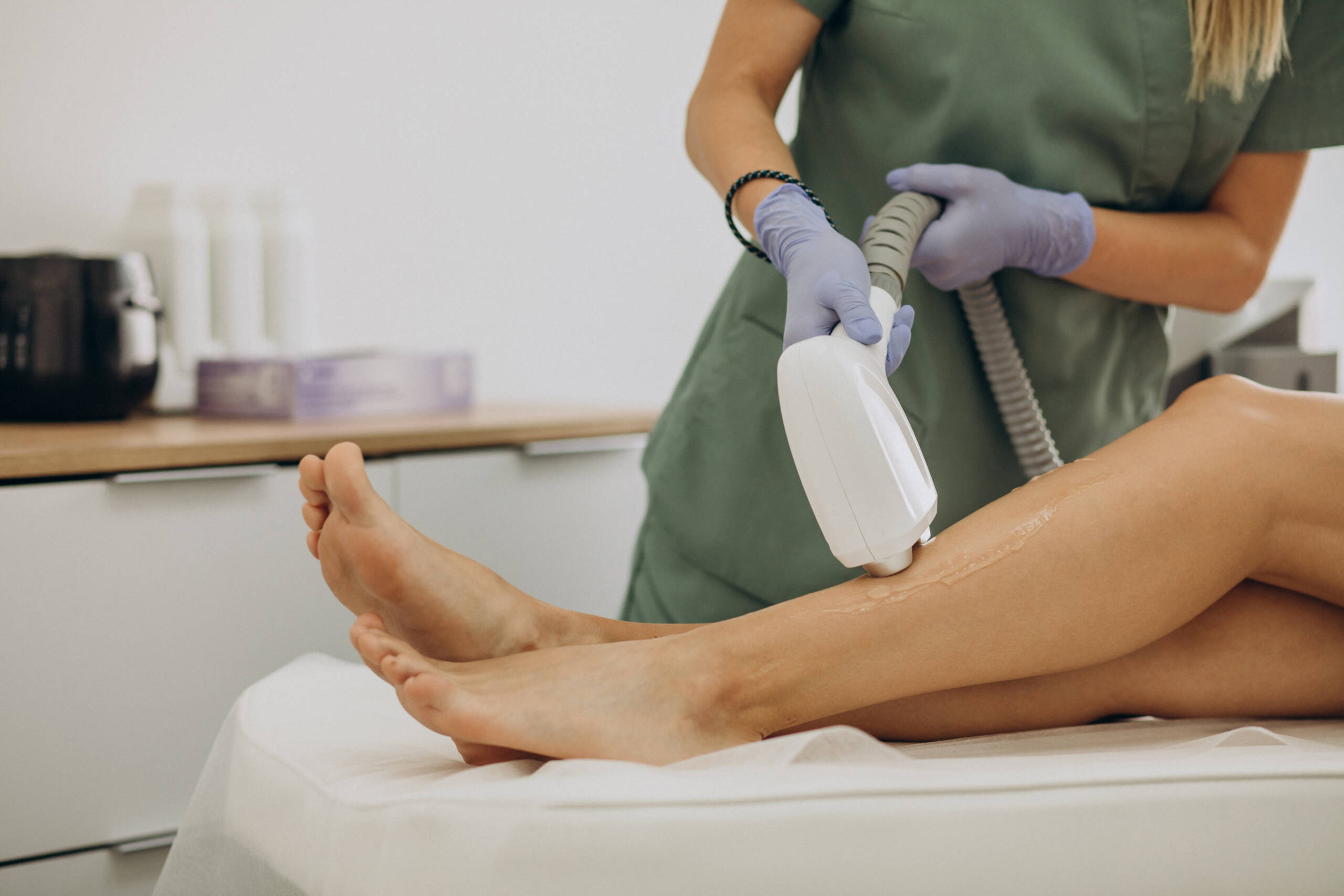 Trattamento di epilazione laser alle gambe eseguito da un’estetista con apparecchiatura professionale.