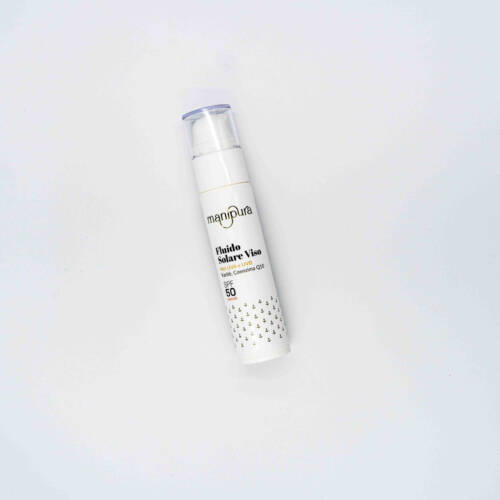 Flacone del Fluido Solare Viso SPF 50 di Manipura, fotografato dall’alto su sfondo bianco, con tappo trasparente e packaging bianco decorato.