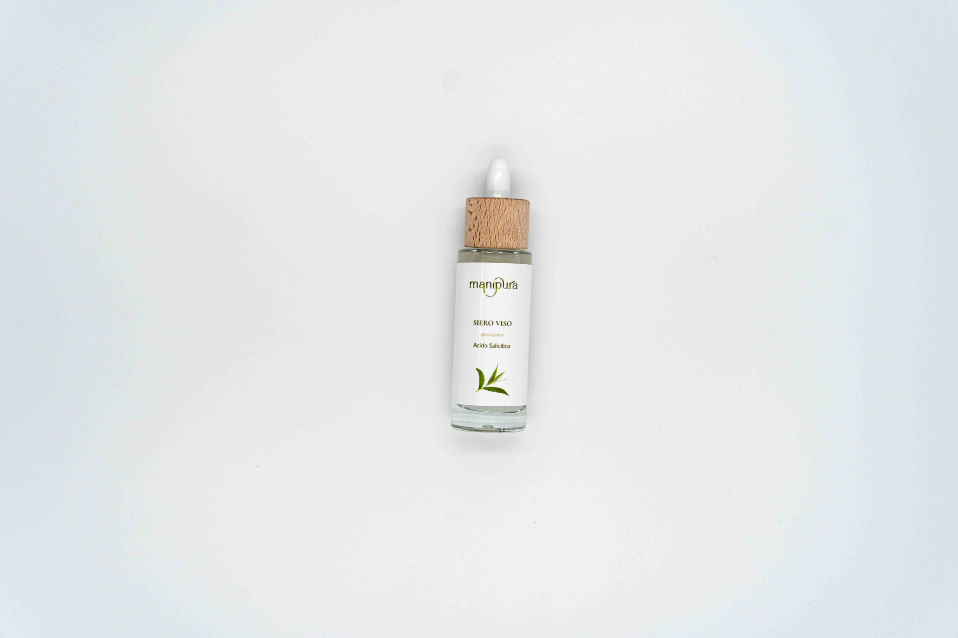 Flacone frontale del siero viso Manipura all’acido salicilico con tappo in legno e contagocce bianco, fotografato su sfondo chiaro.
