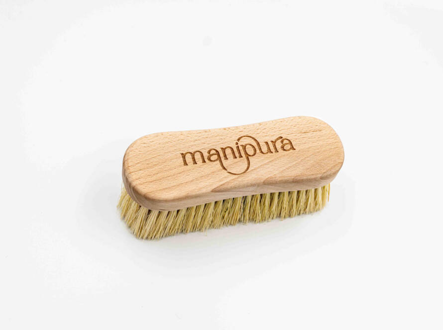 Spazzola in legno naturale con incisione del logo Manipura vista dall’alto su sfondo bianco