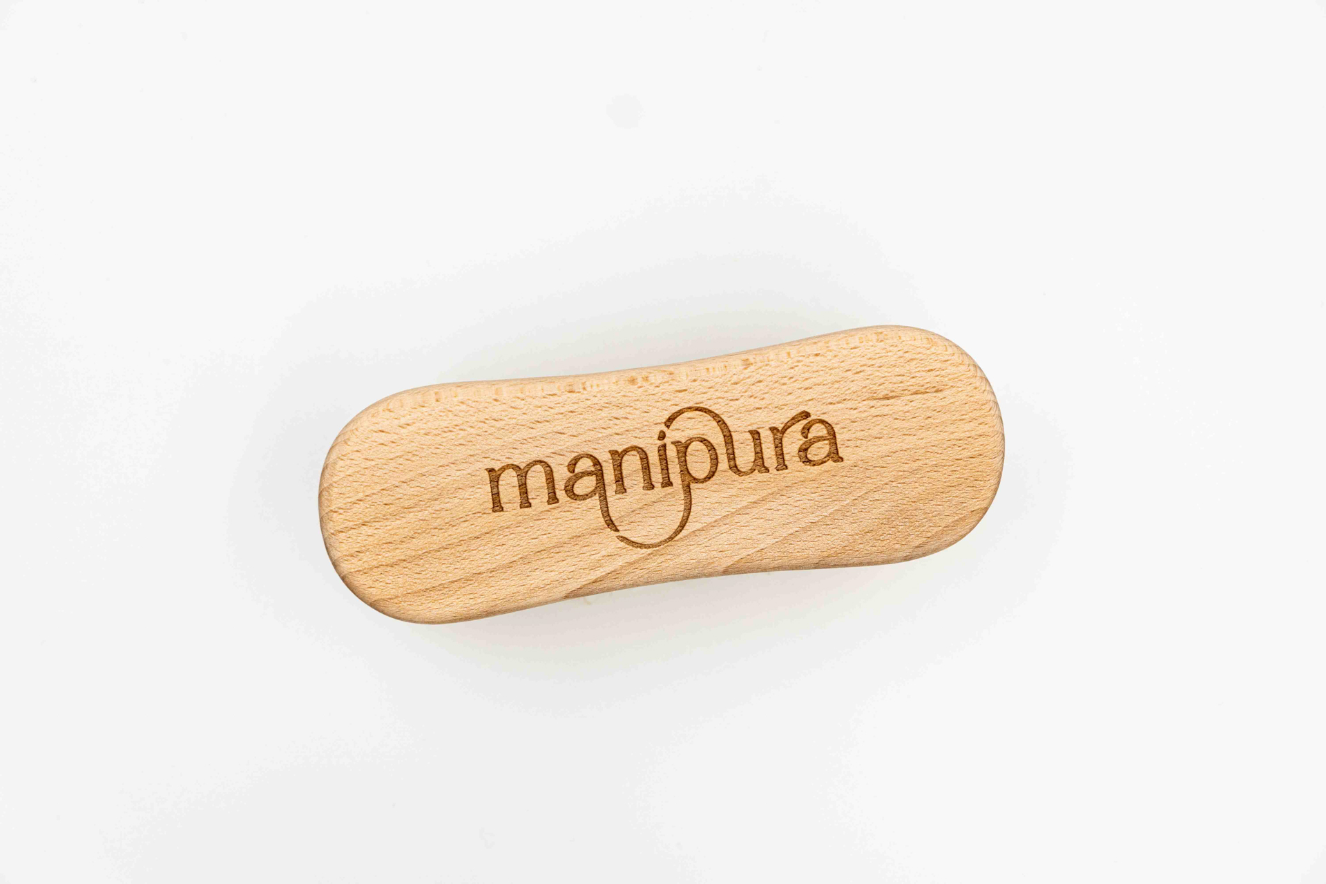 Spazzola in legno naturale con incisione del logo Manipura vista dall’alto su sfondo bianco
