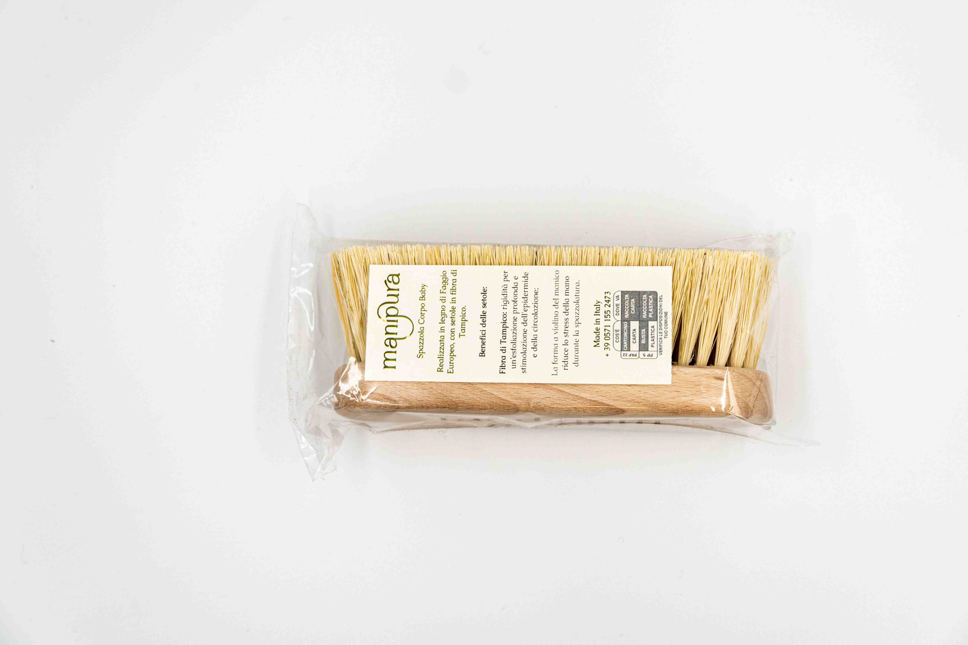 Spazzola corpo baby Manipura in legno di faggio con setole naturali, confezionata in bustina trasparente, vista dall’alto su sfondo bianco.