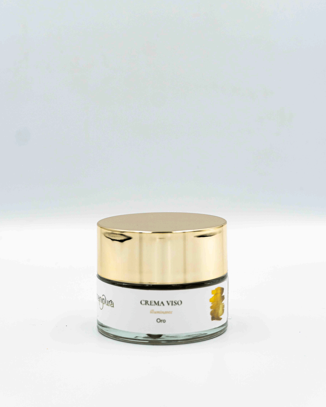 Vasetto frontale di crema viso illuminante Manipura con tappo dorato e dettaglio grafico oro su sfondo bianco.