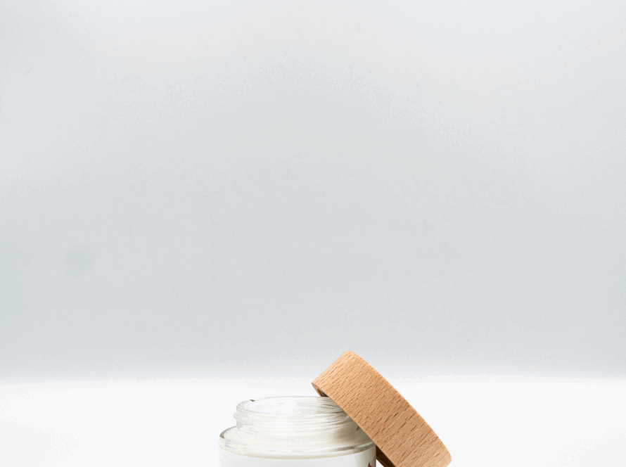 Vasetto della crema viso Rosa Damascena di Manipura con tappo in legno, appoggiato su sfondo bianco.