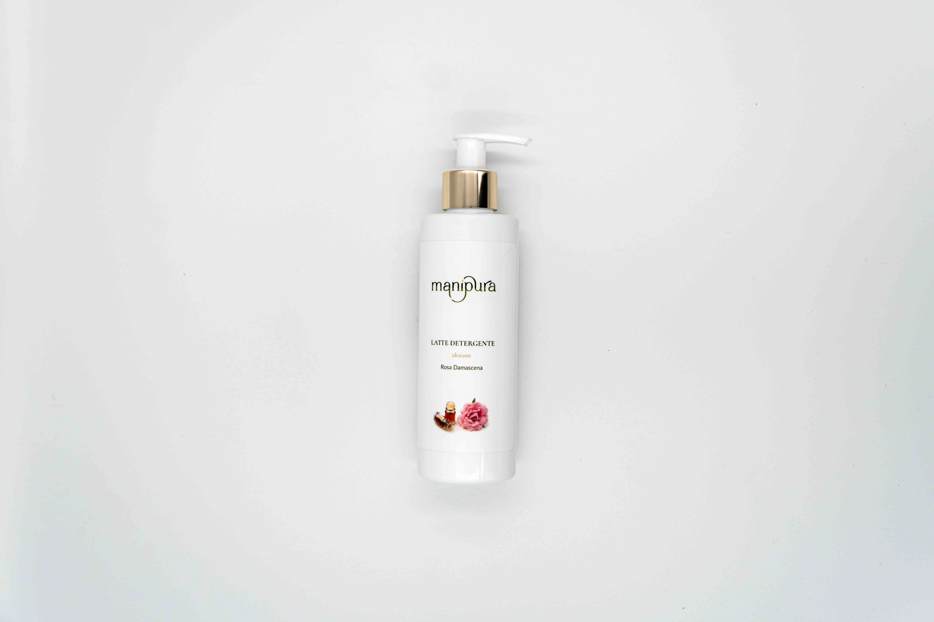 Flacone visto dall’alto del latte detergente idratante Manipura alla Rosa Damascena con dispenser bianco e oro, su sfondo chiaro.