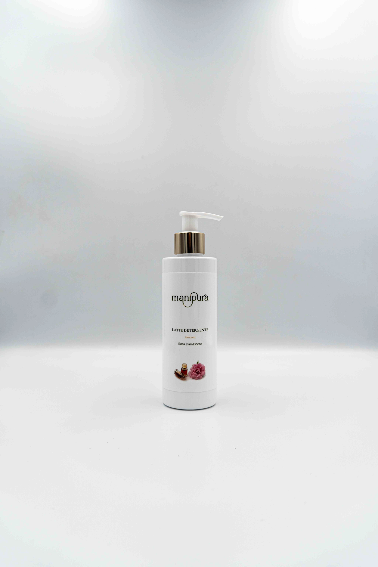 Flacone frontale del latte detergente idratante Manipura alla Rosa Damascena con dispenser bianco e oro, fotografato su sfondo chiaro.
