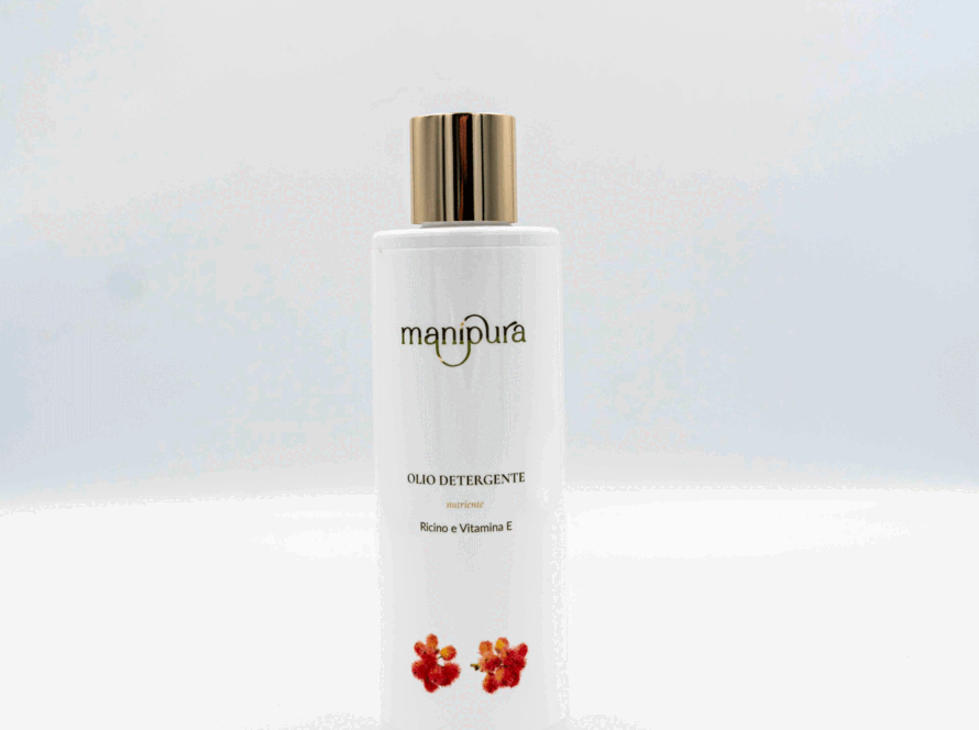 Flacone frontale di olio detergente Manipura con ricino e vitamina E, tappo dorato e grafica floreale su sfondo bianco.