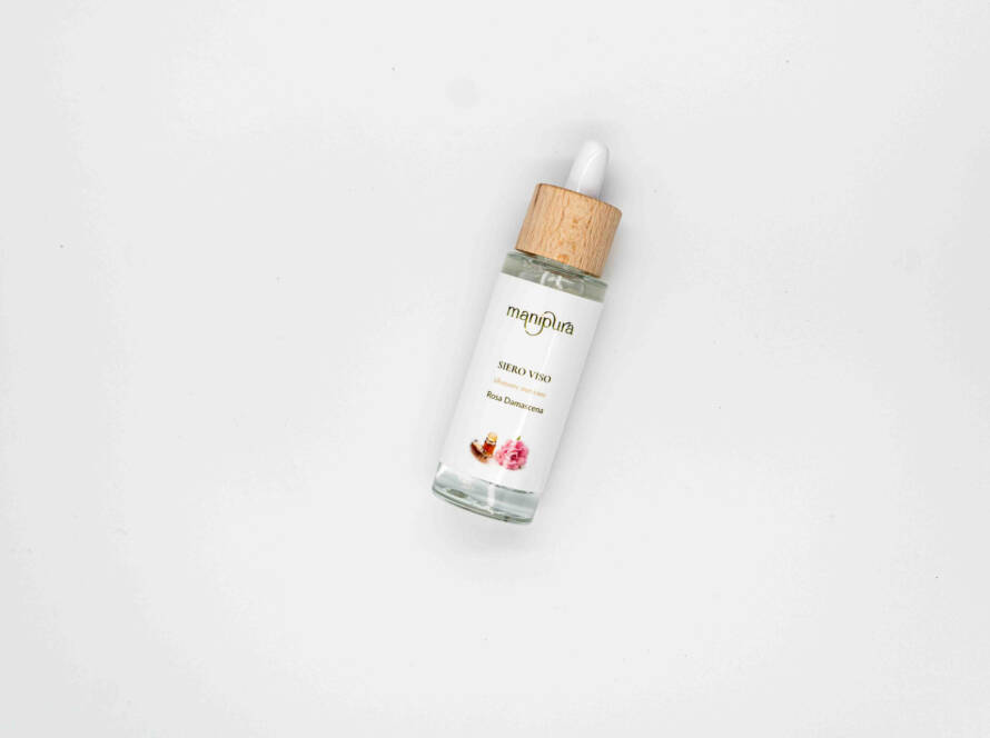 Flacone di siero viso Manipura alla Rosa Damascena con tappo in legno e contagocce, appoggiato su sfondo bianco.