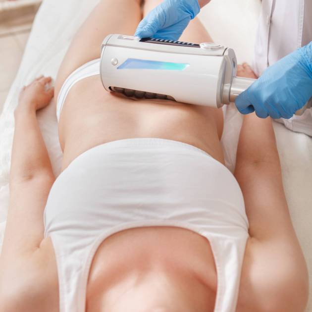 Vertical shot of a woman enjoying full body slimming treatment with endospheres device at cosmetology salon